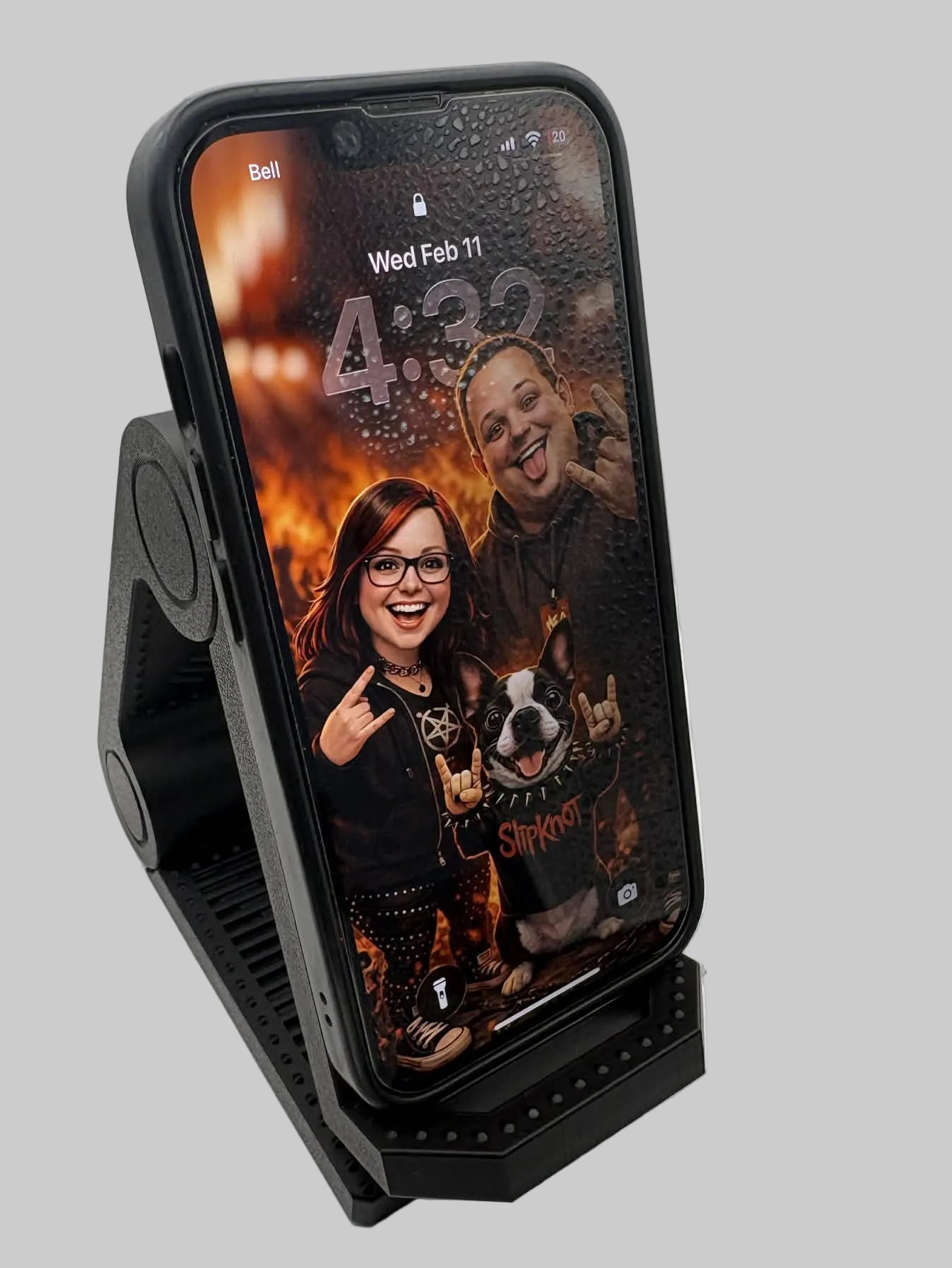 Phone with a case on a stand displaying a photo of two people and a dog.